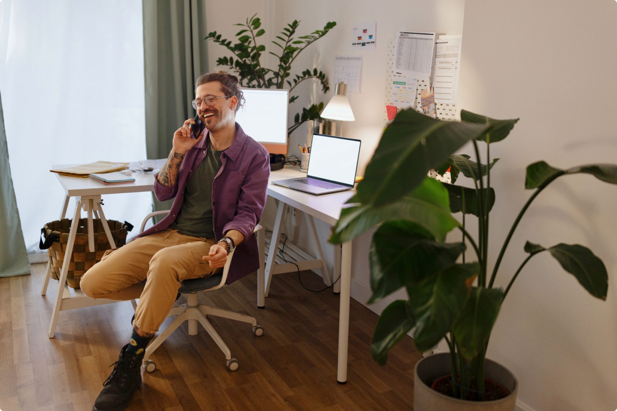 Mann sitzt lachend und telefonierend am Schreibtisch